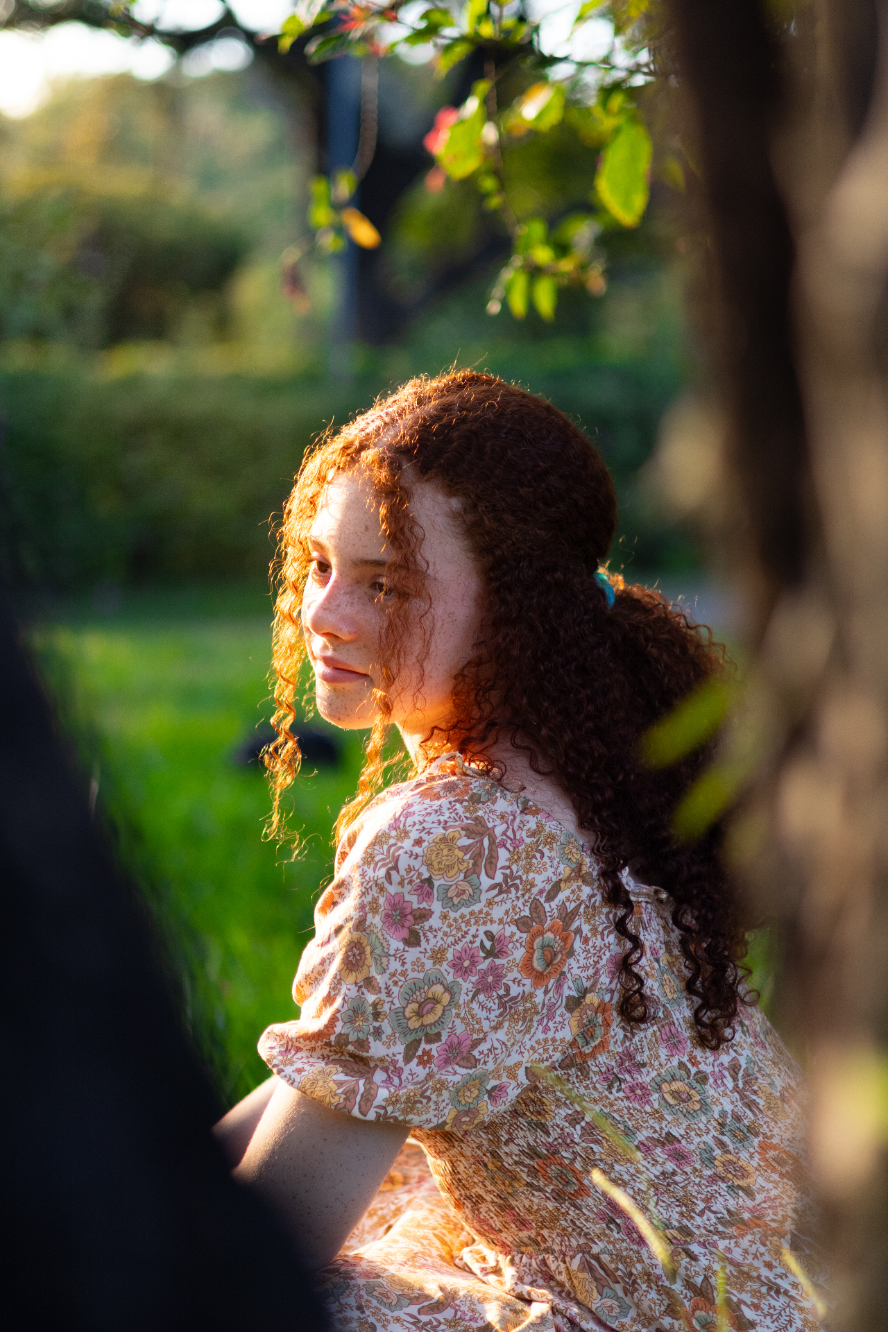 Allana de perfil em um jardim iluminado pelo fim de tarde
